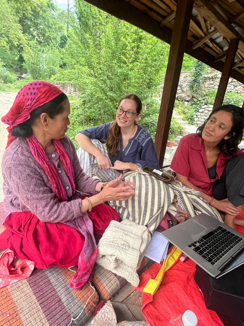 Nüwa Mano founders talk with an artisan all sitting together on the floor