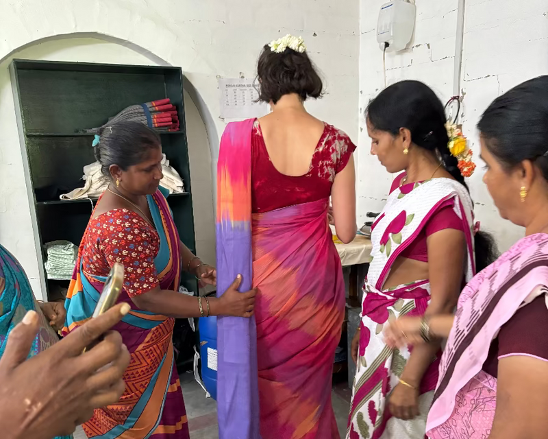 Group of Porgai artisans in colorful sarees dressing Nüwa Mano founder in saree for  wedding.