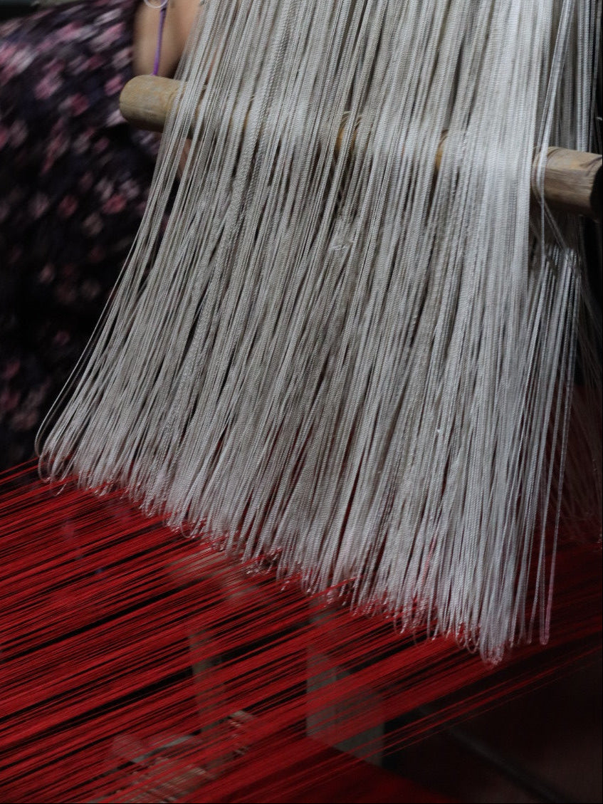 Person working with a large bundle of thin sticks or reeds in a workshop setting.