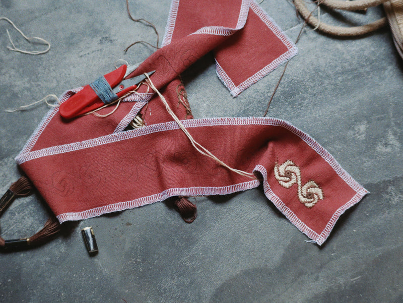 Red paprika Nüwa pants embroidery in progress, sitting on the floor half finished.