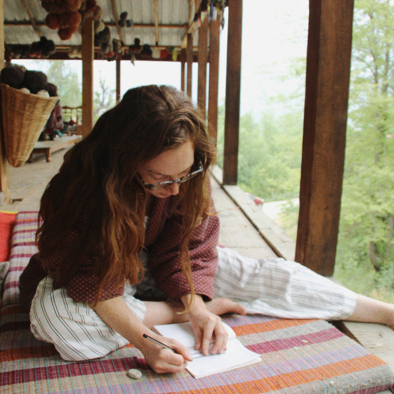 Nüwa Mano founder works at artisan stuido with notebook on a cushion