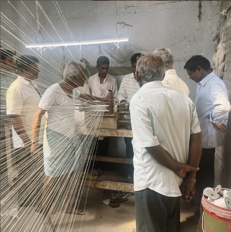 men working together with cotton thread hanging across the room